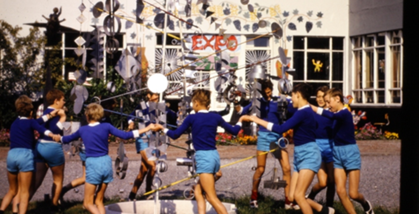 Oude foto van kinderen die in een kring rond kunstwerk dansen